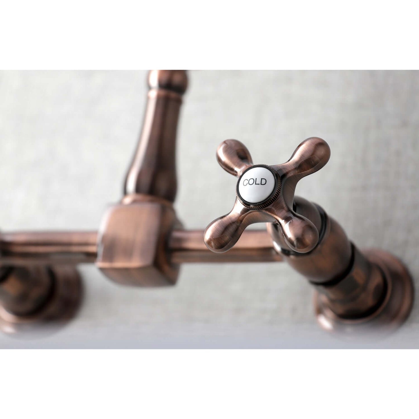 Kingston Brass double-handle 2-hole wall-mount bridge kitchen faucet in copper with a 'Cold' label on a white background