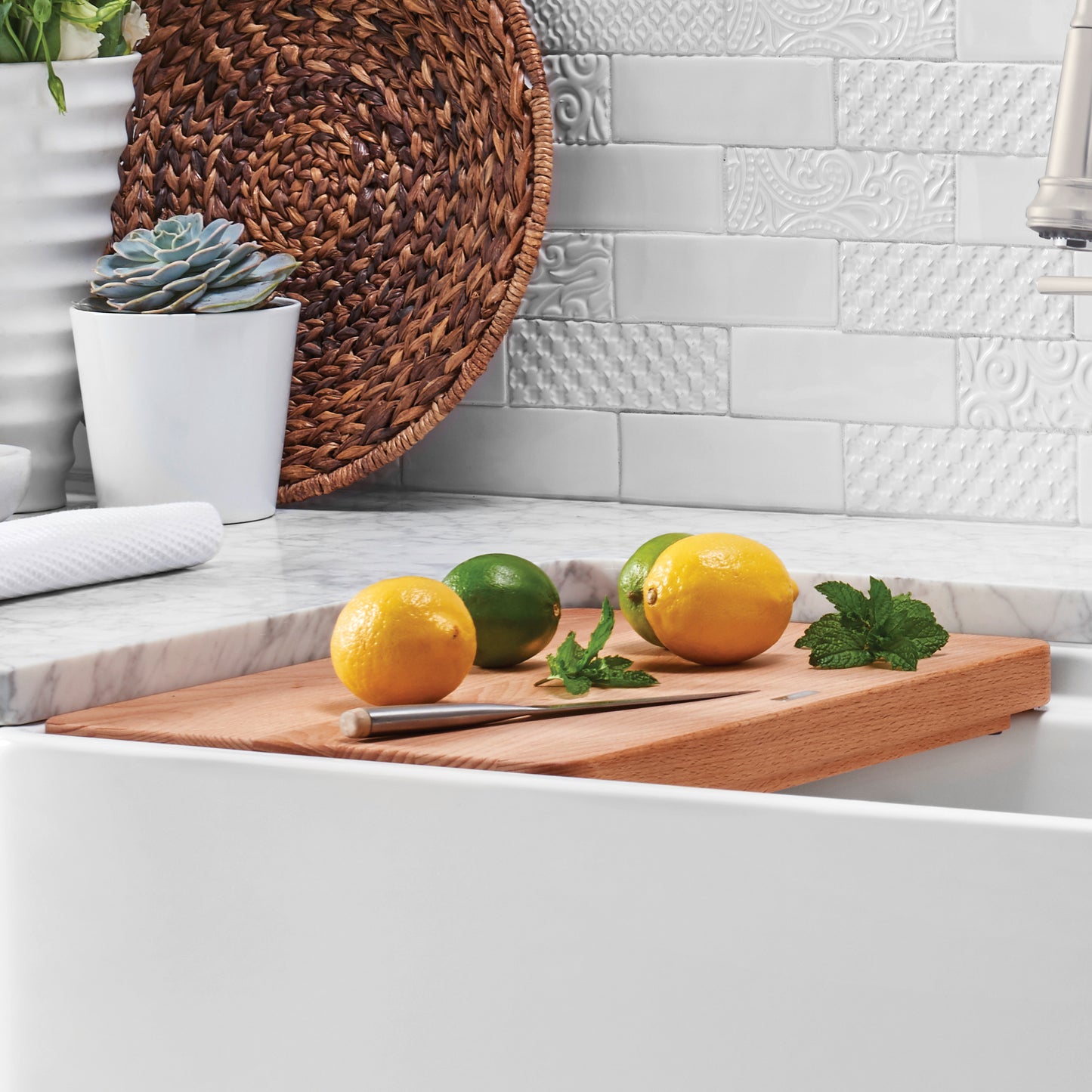 BLANCO PROFINA Beechwood Cutting Board with fresh lemons, limes, and mint on a kitchen sink.