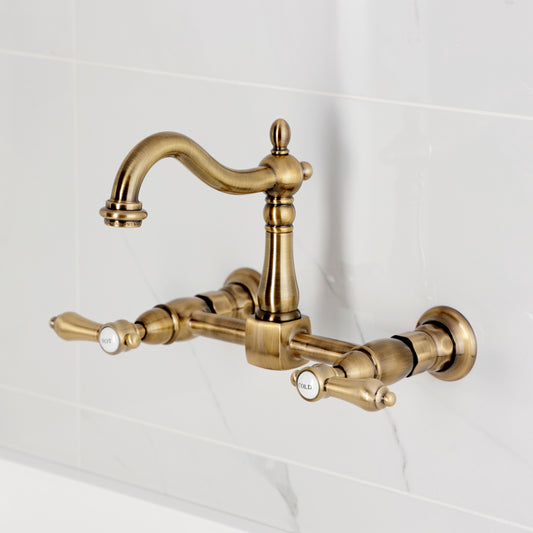 Kingston KS1263BAL Heirloom Two-Handle Wall Mount Bridge Kitchen Faucet, Antique Brass on a white tile background.