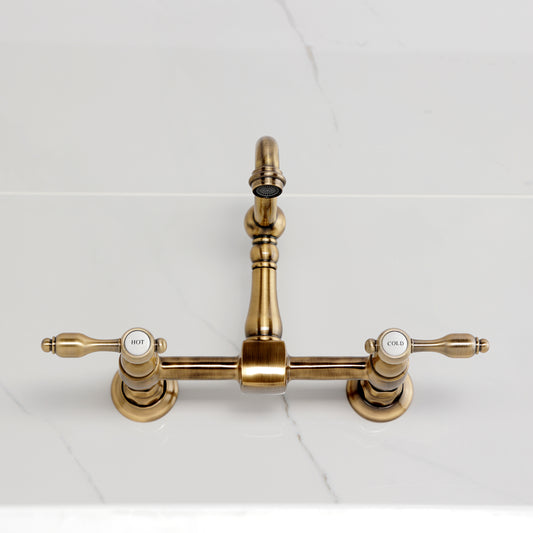 Kingston KS2443TAL Tudor Two-Handle Wall Mount Bridge Kitchen Faucet, Antique Brass on marble countertop
