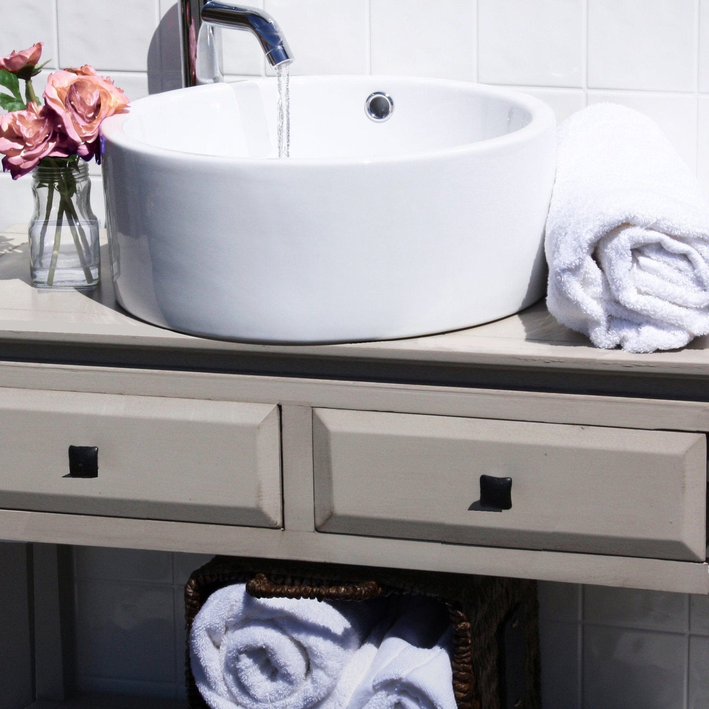 Nantucket Round White Vessel Sink With Overflow - NSV213 displayed on a countertop with flowers and towels.