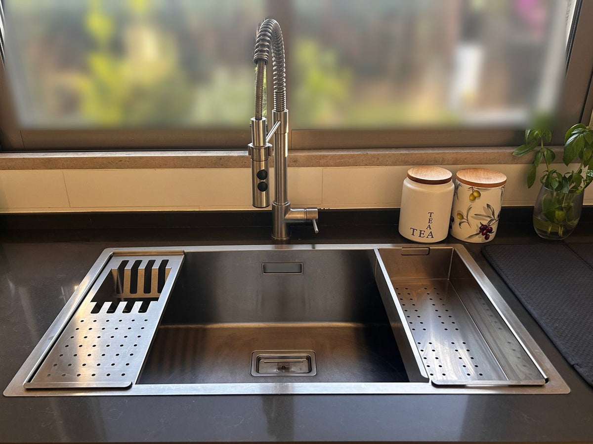 Clare's stainless steel workstation sink with a shallow strainer and deep colander on the ledge
