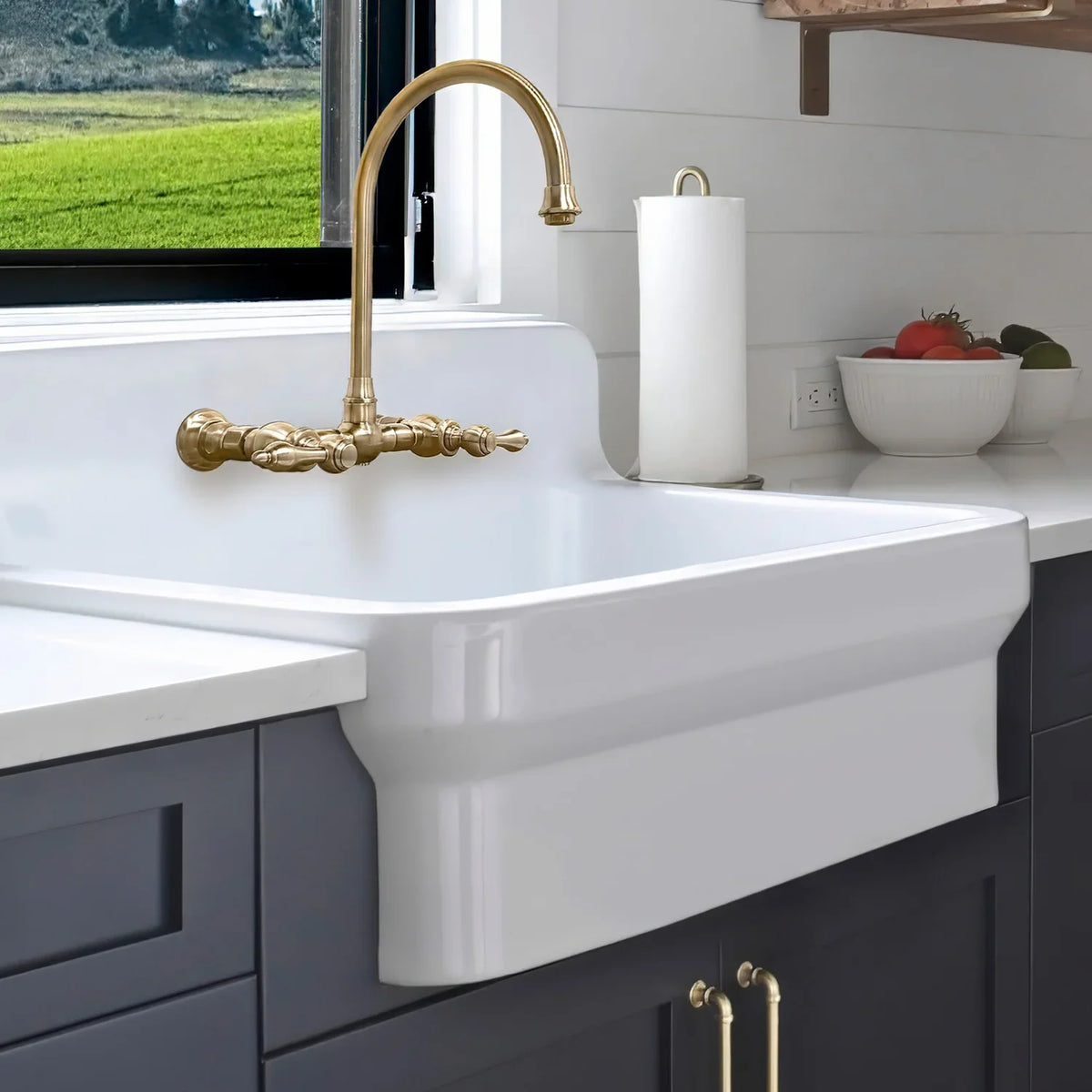 Whitehaus fireclay farmhouse sink with high backsplash, deep navy cabinets and a gold bridge faucet
