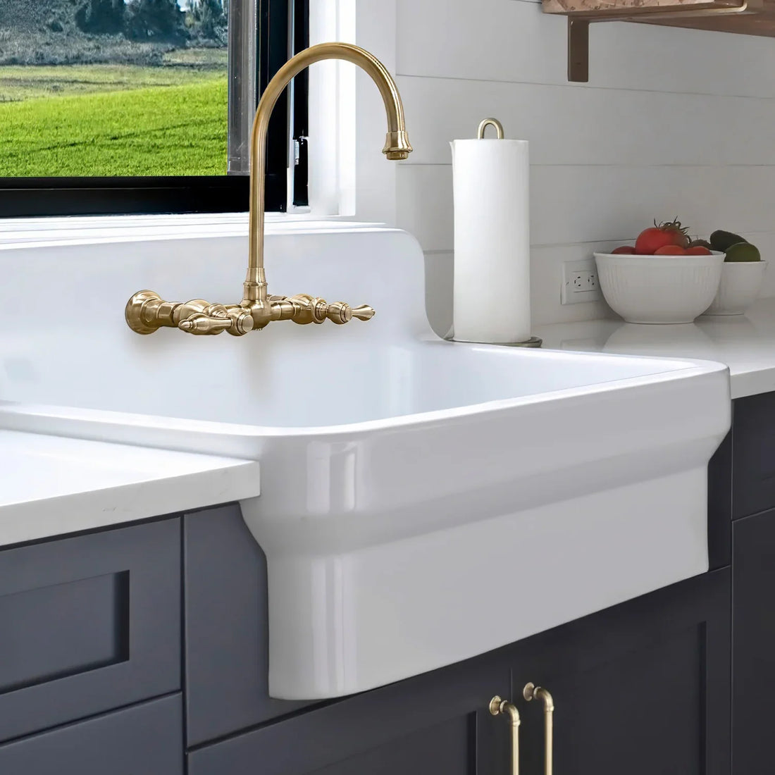 Whitehaus fireclay farmhouse sink with high backsplash, deep navy cabinets and a gold bridge faucet