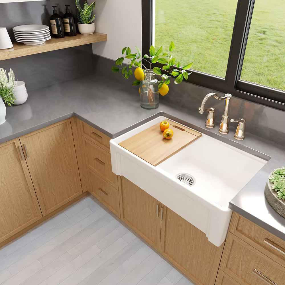 Modern kitchen with a white Nantucket 33 inch Dennis sink, showing arched side and a window view of greenery.