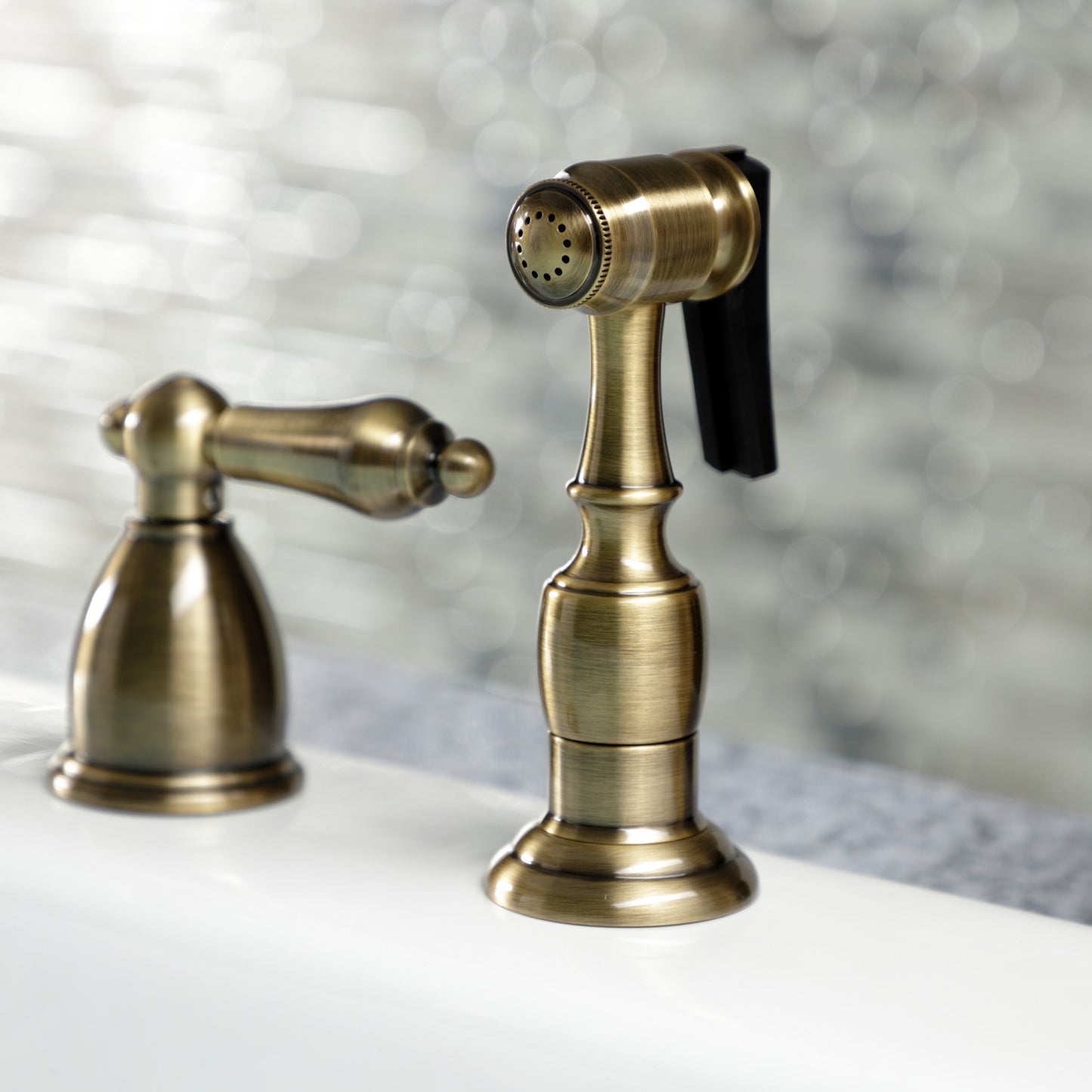 Kingston Brass "Antique Brass" widespread kitchen faucet  with spray head accessory on a blurred background