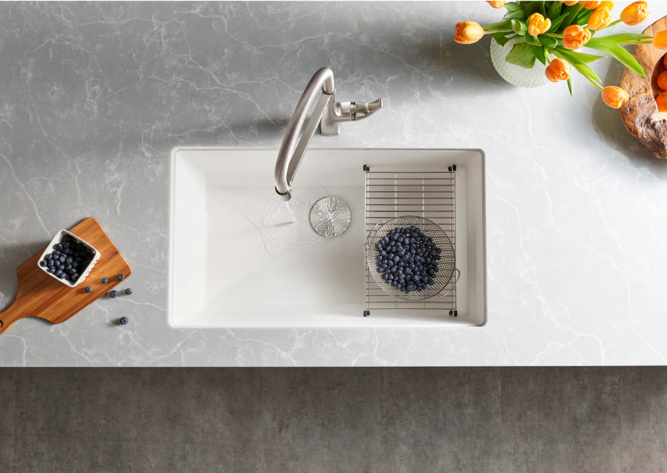 Blanco Silgranit 32inch white kitchen sink with silver faucet on a gray countertop with blueberries
