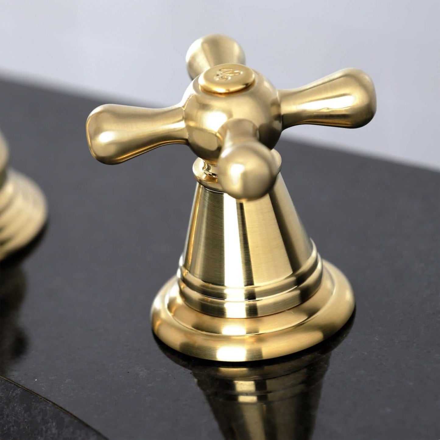 Close-up of the handle of the KINGSTON Brass Widespread Bathroom Faucet with Pop-Up Drain - FSC1979AAX on a black surface.