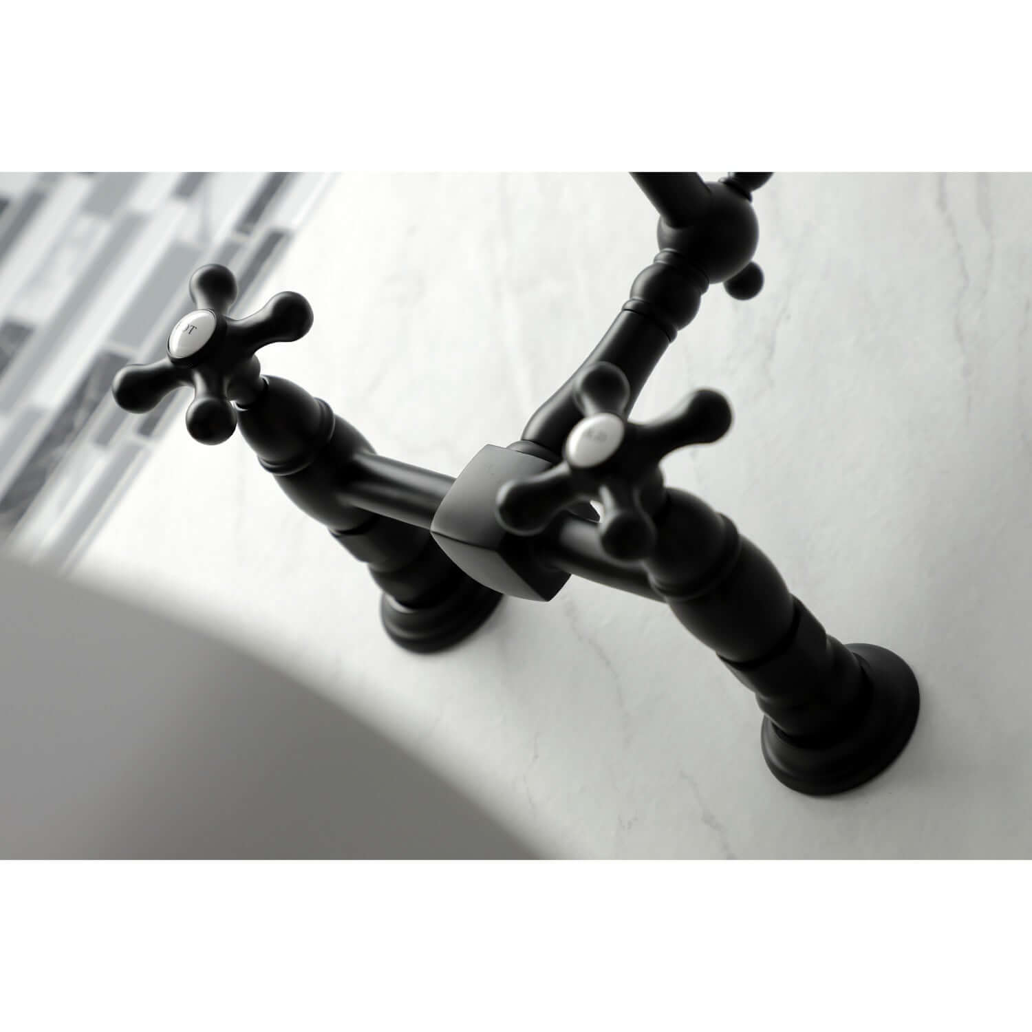 Kingston Brass matte black double-handle 2-hole wall-mount bridge kitchen faucet on a white sink with blurred background