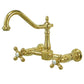 Kingston Brass polished brass double-handle 2-hole wall-mount bridge kitchen faucet on a white background