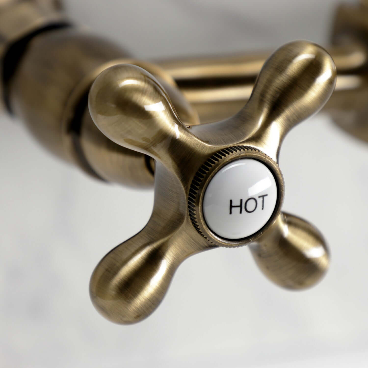 Kingston Brass antique brass double-handle 2-hole wall-mount bridge kitchen faucet faucet handle with 'HOT' label on a white background