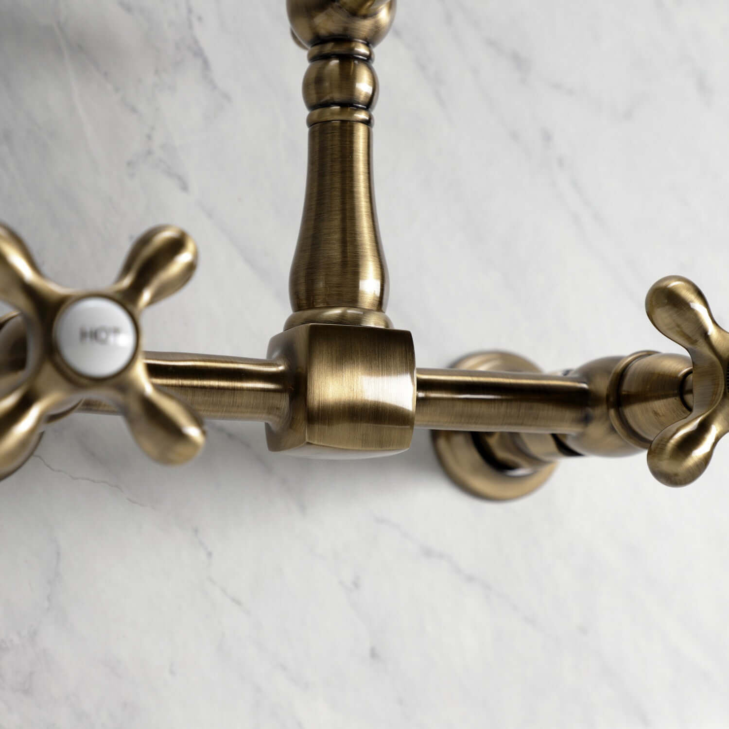 Kingston Brass antique brass double-handle 2-hole wall-mount bridge kitchen faucet on a marble background