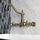 Kingston Brass antique brass double-handle 2-hole wall-mount bridge kitchen faucet on a marble wall with tiled background