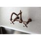 Kingston Brass antique copper double-handle 2-hole wall-mount bridge kitchen faucet on a light gray tiled wall with a stainless steel sink.