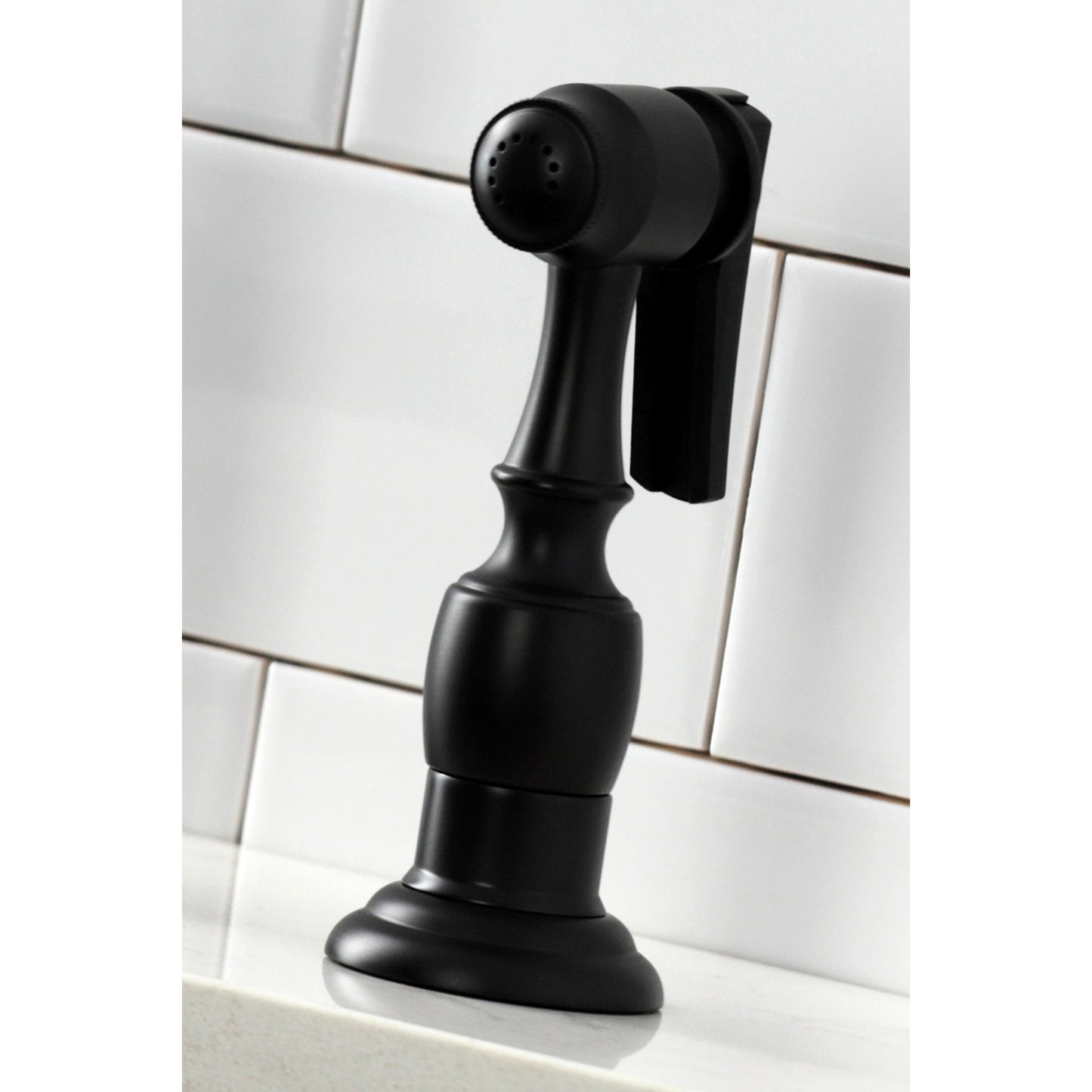KINGSTON Brass Heritage Bridge Kitchen Faucet with Brass Sprayer in black sprayer side view on countertop.