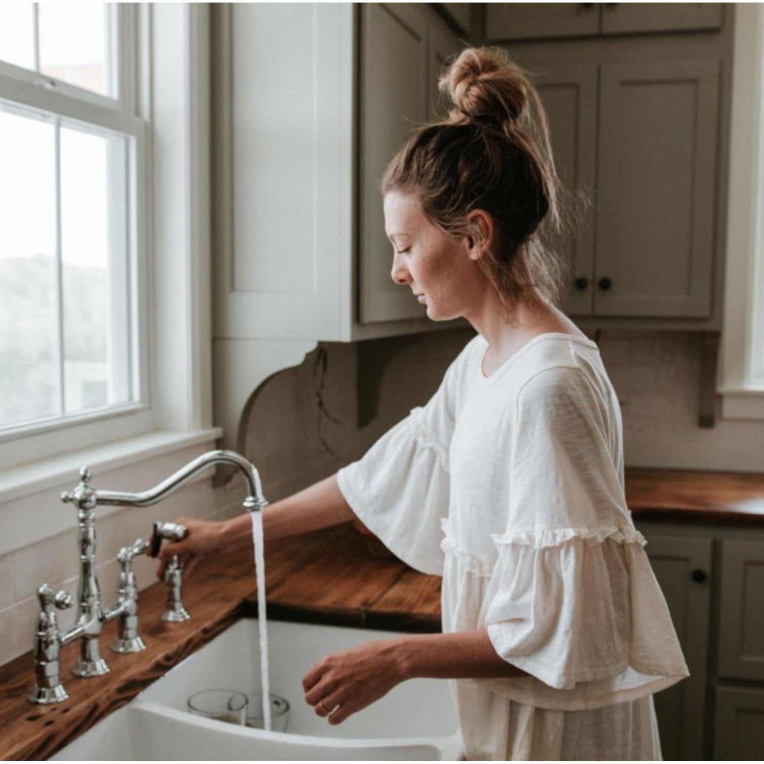 Woman washing hands in a kitchen sink with a vintage style Kingston Brass KS1271ALBS  polished chrome faucet.