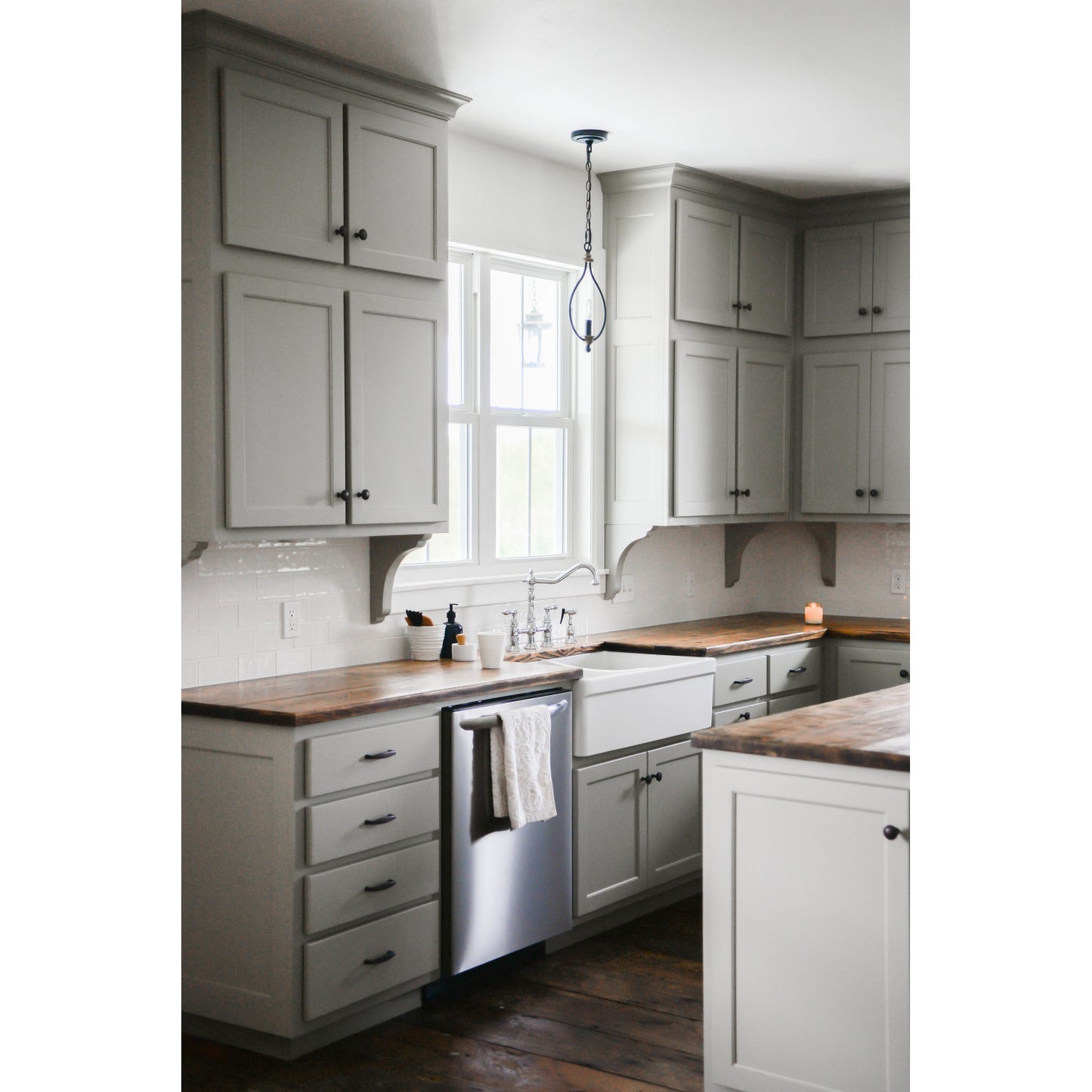 Kingston Brass KS1271ALBS  polished chrome faucet in a modern kitchen with white cabinets, wooden countertops, and a window above the sink.