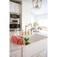 Modern kitchen with white countertops, Kingston Brass KS1272ALBS polished brass faucet, and pink flowers.