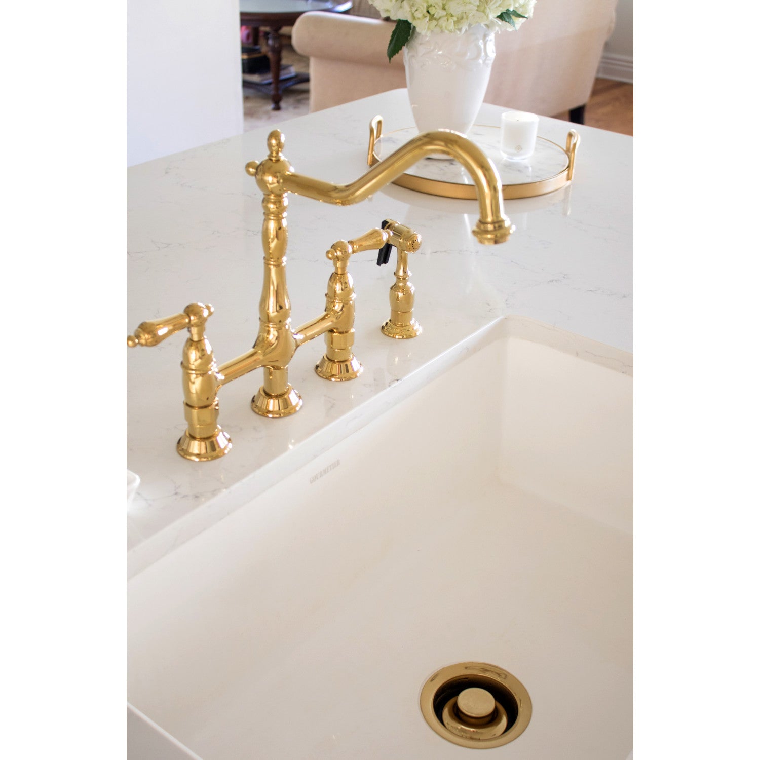 Kingston Brass KS1272ALBS polished brass kitchen faucet on a white sink in a kitchen setting