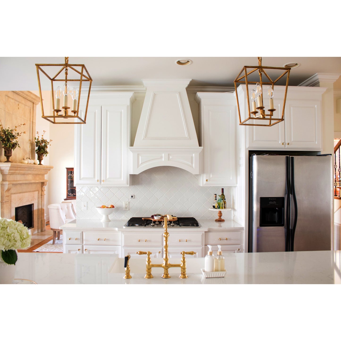Modern kitchen with white cabinets, Kingston Brass KS1272ALBS polished brass faucet, and brass pendant lights