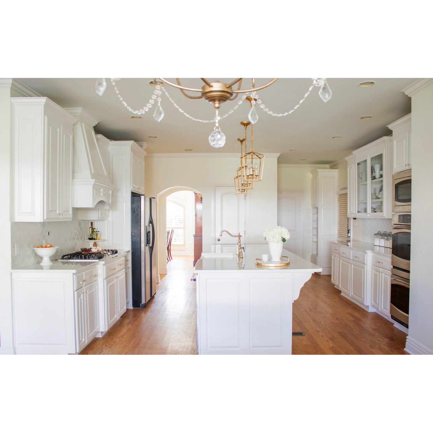 Modern kitchen interior featuring KINGSTON Brass Heritage Bridge Kitchen Faucet with Brass Sprayer and elegant chandeliers.