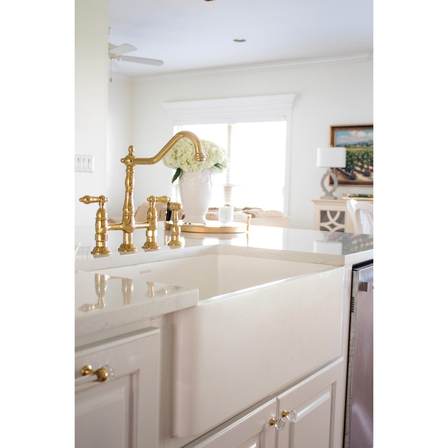 Farmhouse sink with a Kingston Brass KS1272ALBS polished brass faucet and white cabinets