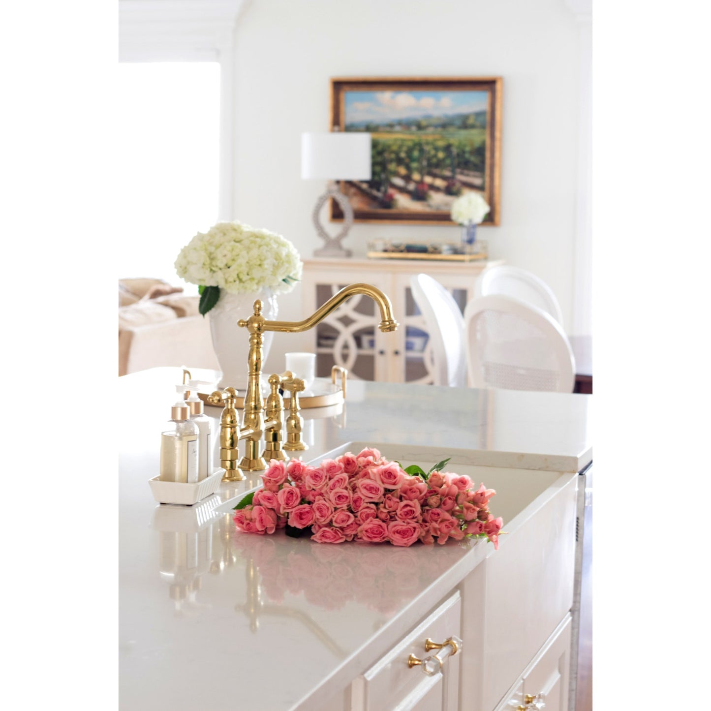 Elegant kitchen with KINGSTON Brass Heritage Bridge Kitchen Faucet with Brass Sprayer and fresh pink roses on the countertop.