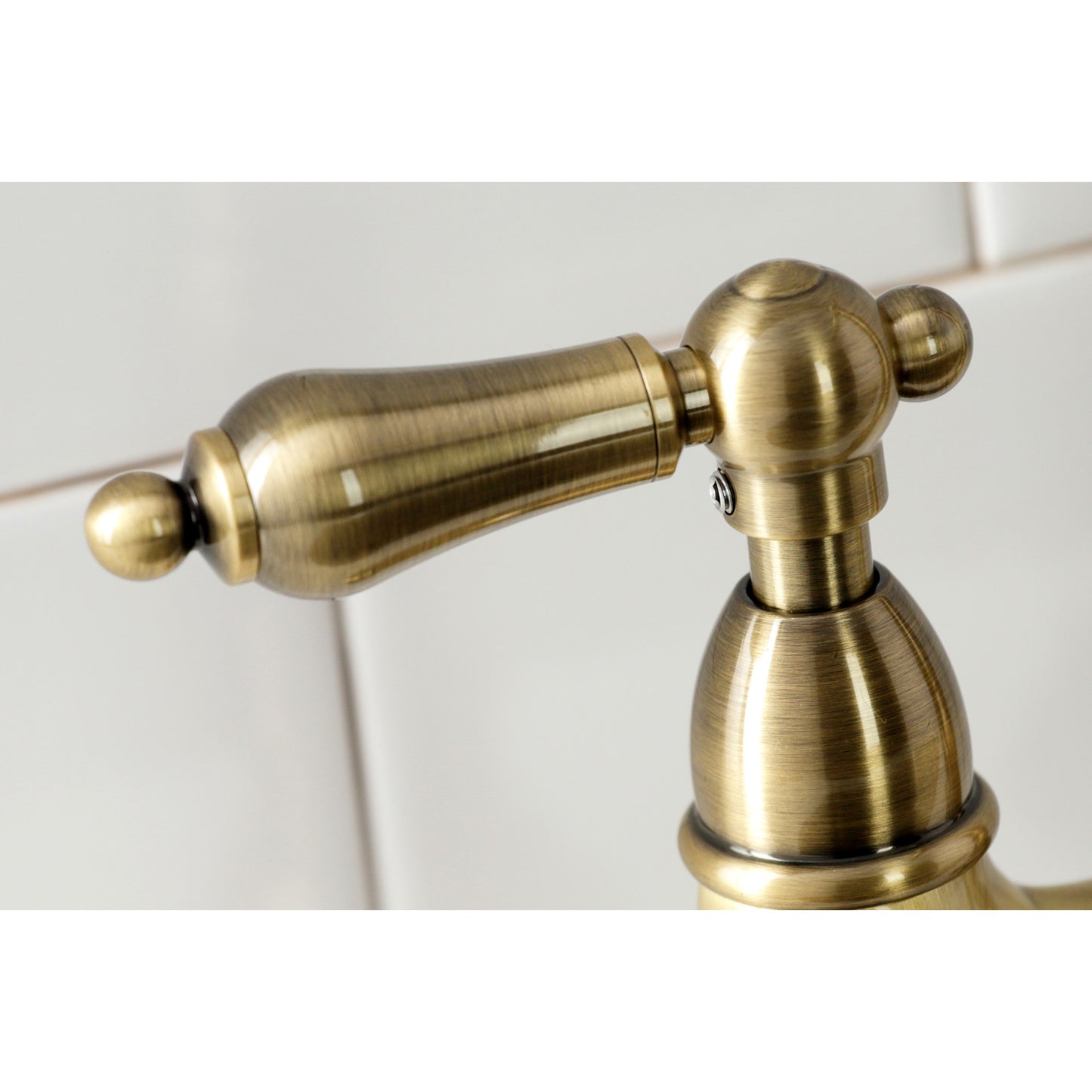 Close up of lever faucet handle for Kingston Brass KS1273ALBS antique brass on a white tiled background