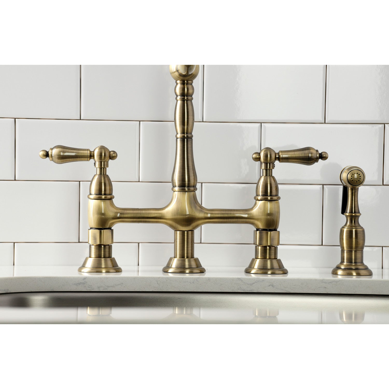 Kingston Brass KS1273ALBS antique brass kitchen bridge faucet with a white tiled backsplash