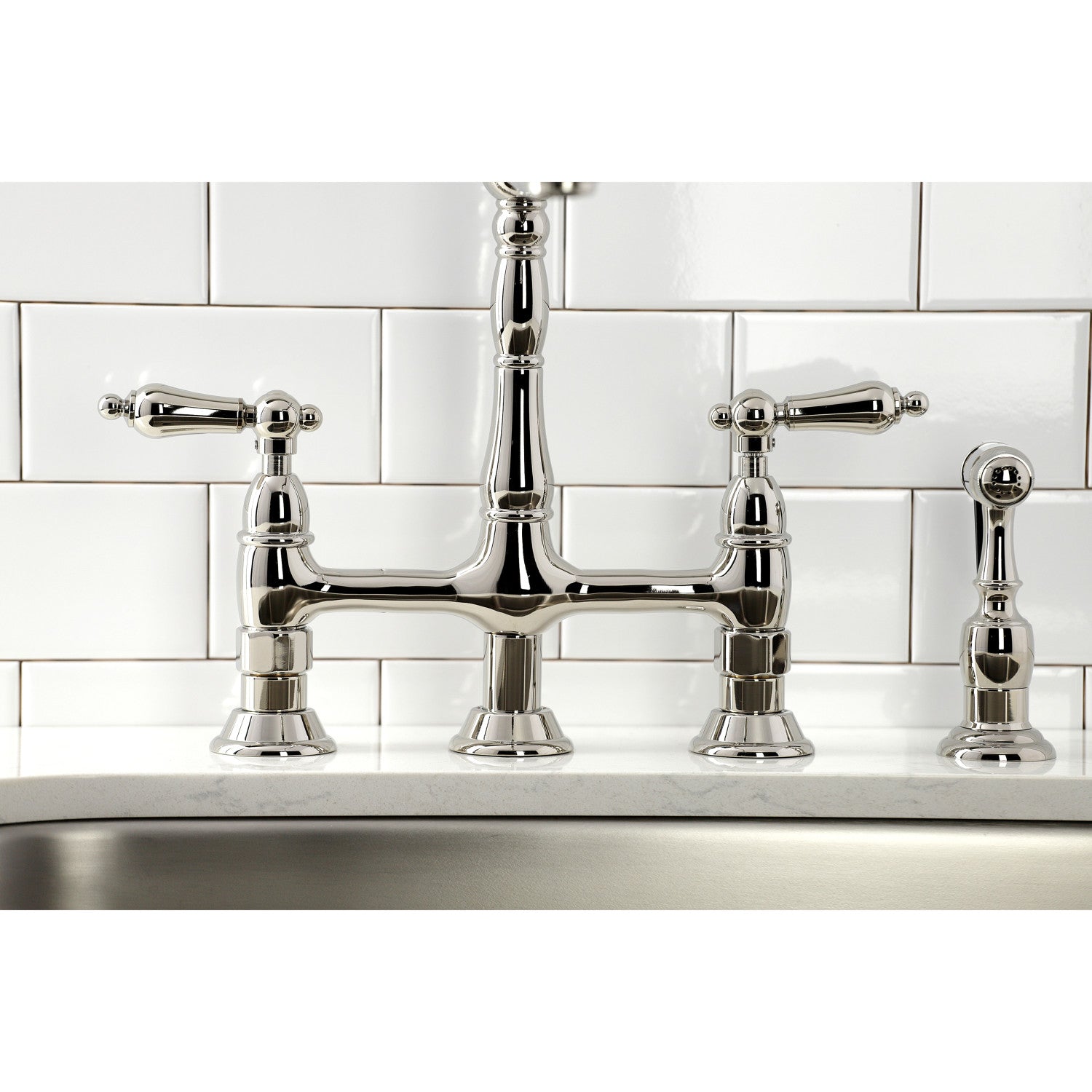 Kingston Brass KS1276ALBS polished nickel bridge faucet with handles on a kitchen sink against a white tiled wall.