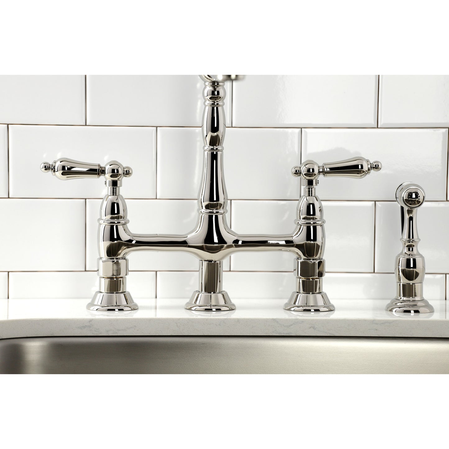 Kingston Brass KS1276ALBS polished nickel bridge faucet with handles on a kitchen sink against a white tiled wall.