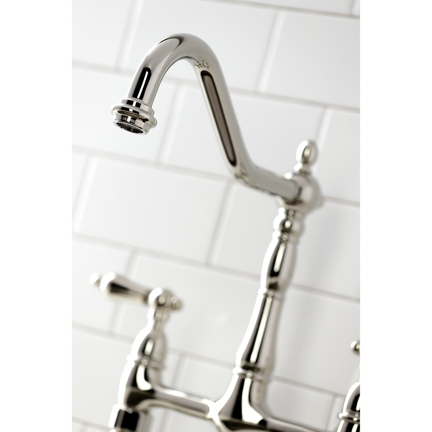 Close up of Kingston Brass KS1276ALBS polished nickel kitchen faucet spout on a white tiled wall