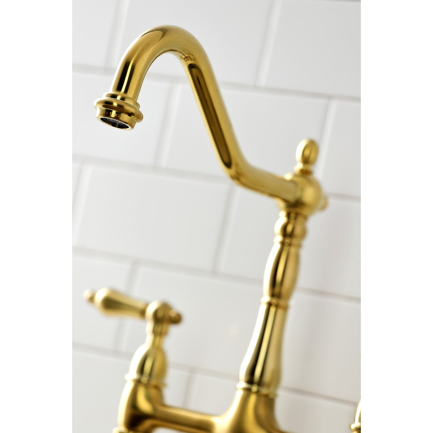 Close-up of the spout of the KINGSTON Brass Heritage Bridge Kitchen Faucet with Brass Sprayer, showcasing its elegant design.