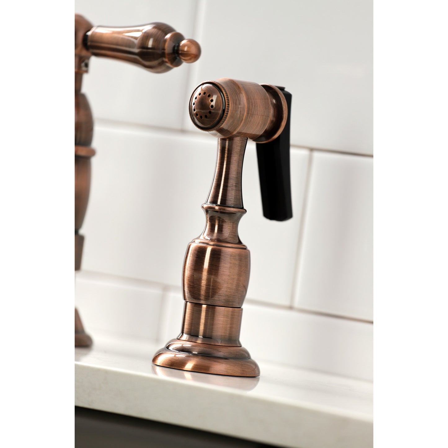 KINGSTON Brass Heritage Bridge Kitchen Faucet with Brass Sprayer close-up of sprayer on countertop.