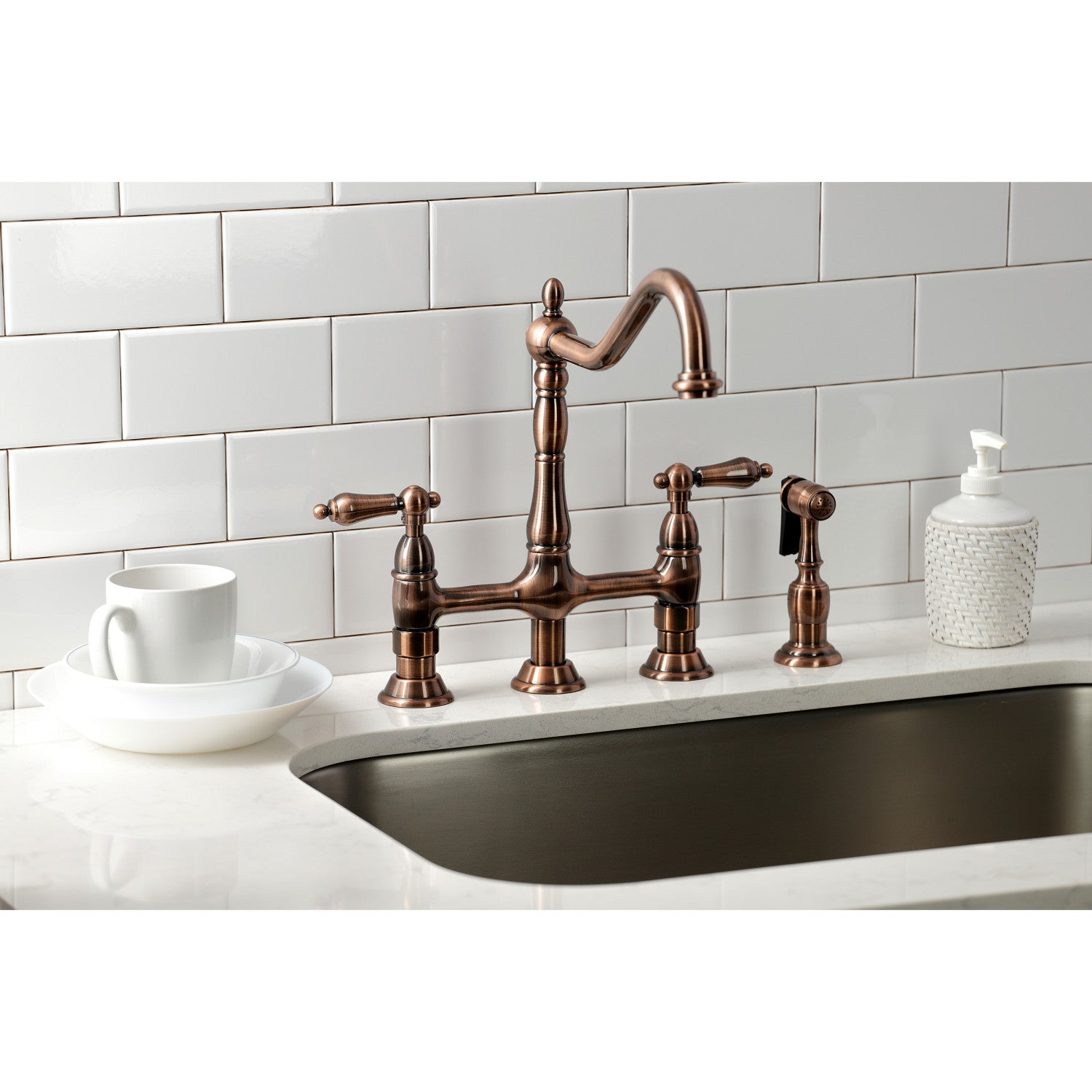 Kingston Brass KS127ALBSAC antique copper kitchen faucet with sink against a white tiled wall and white countertop