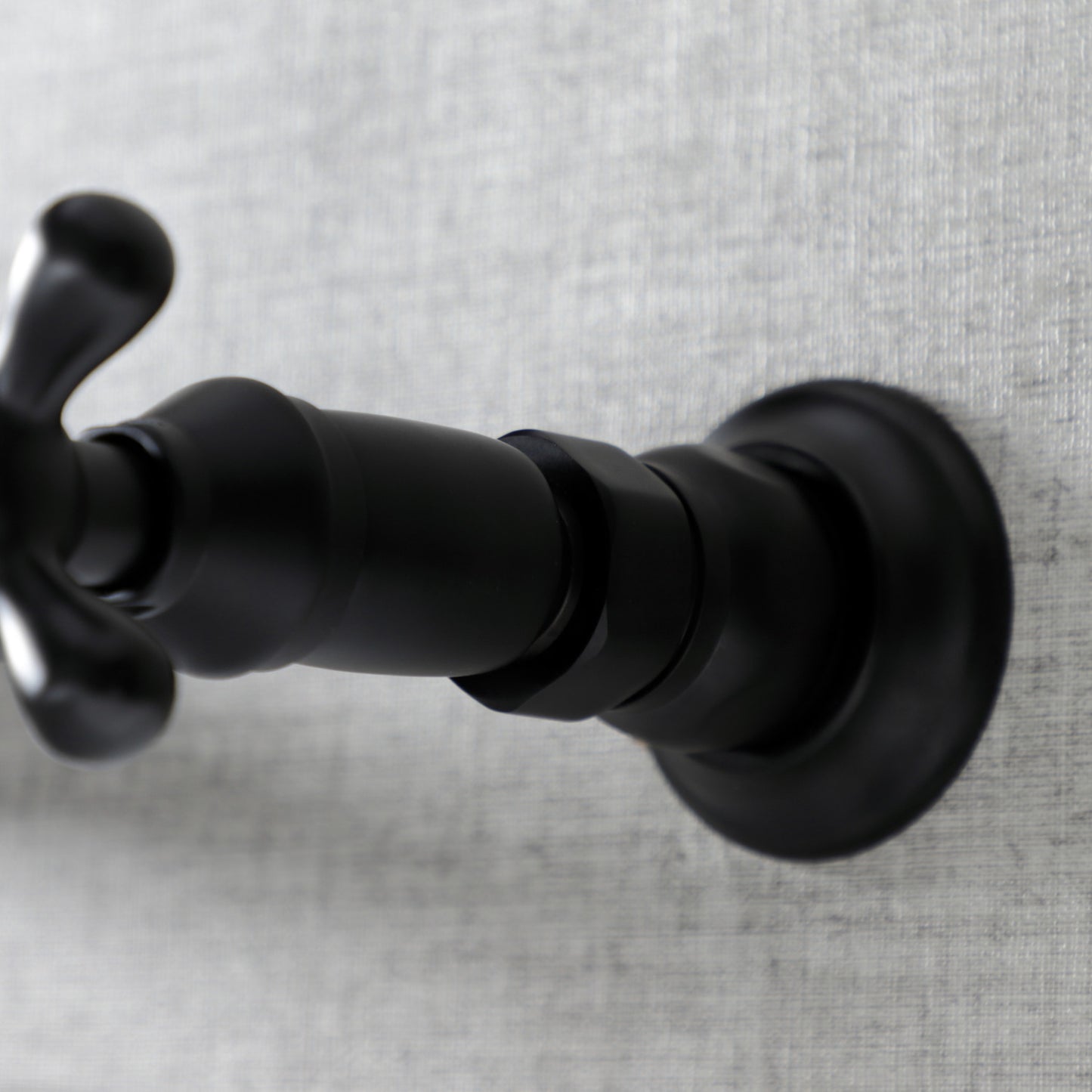 Kingston Brass KS3240AX matte black bathroom faucet handle on a textured gray background