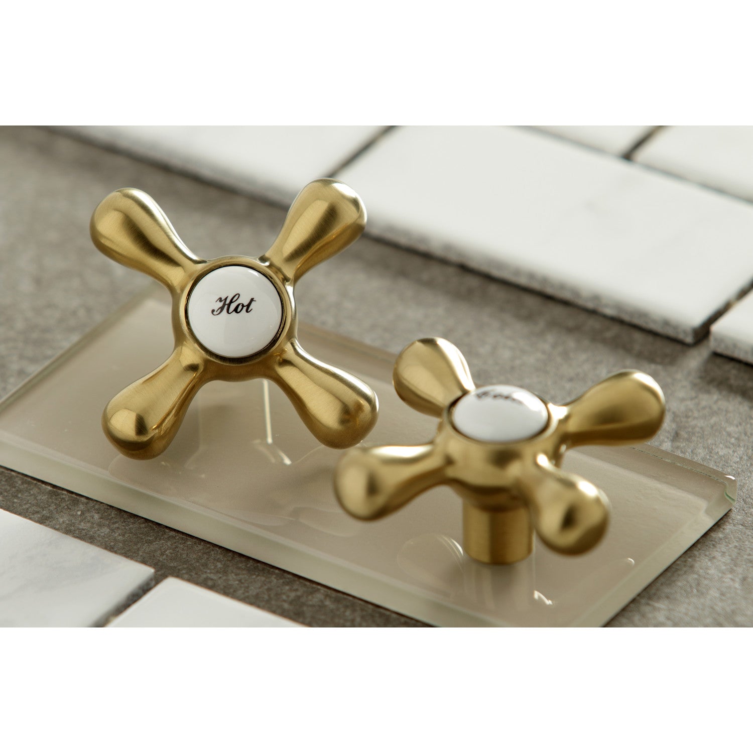 Kingston Brass KS3237AX brushed brass bathroom faucet handle samples on a tiled surface