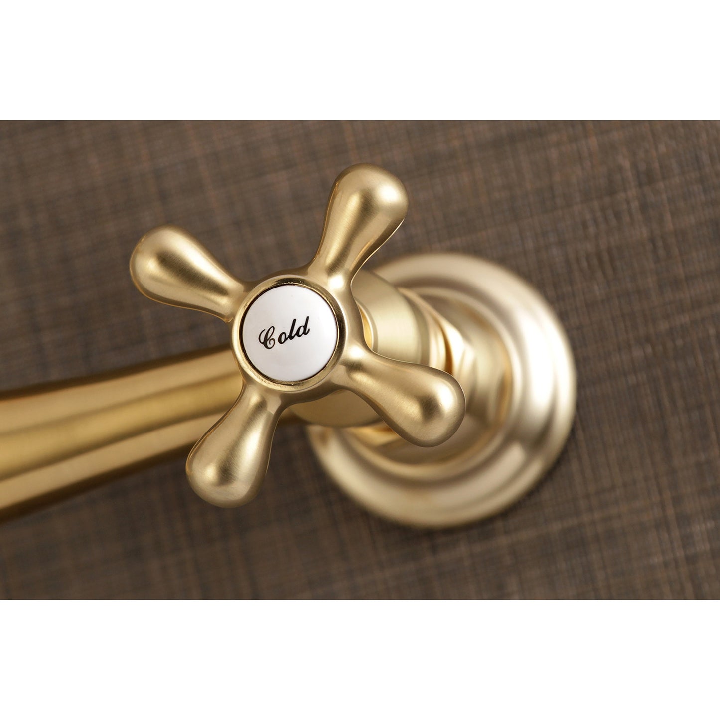 Kingston Brass KS3237AX brushed brass bathroom faucet handle with 'Cold' label on a brown background