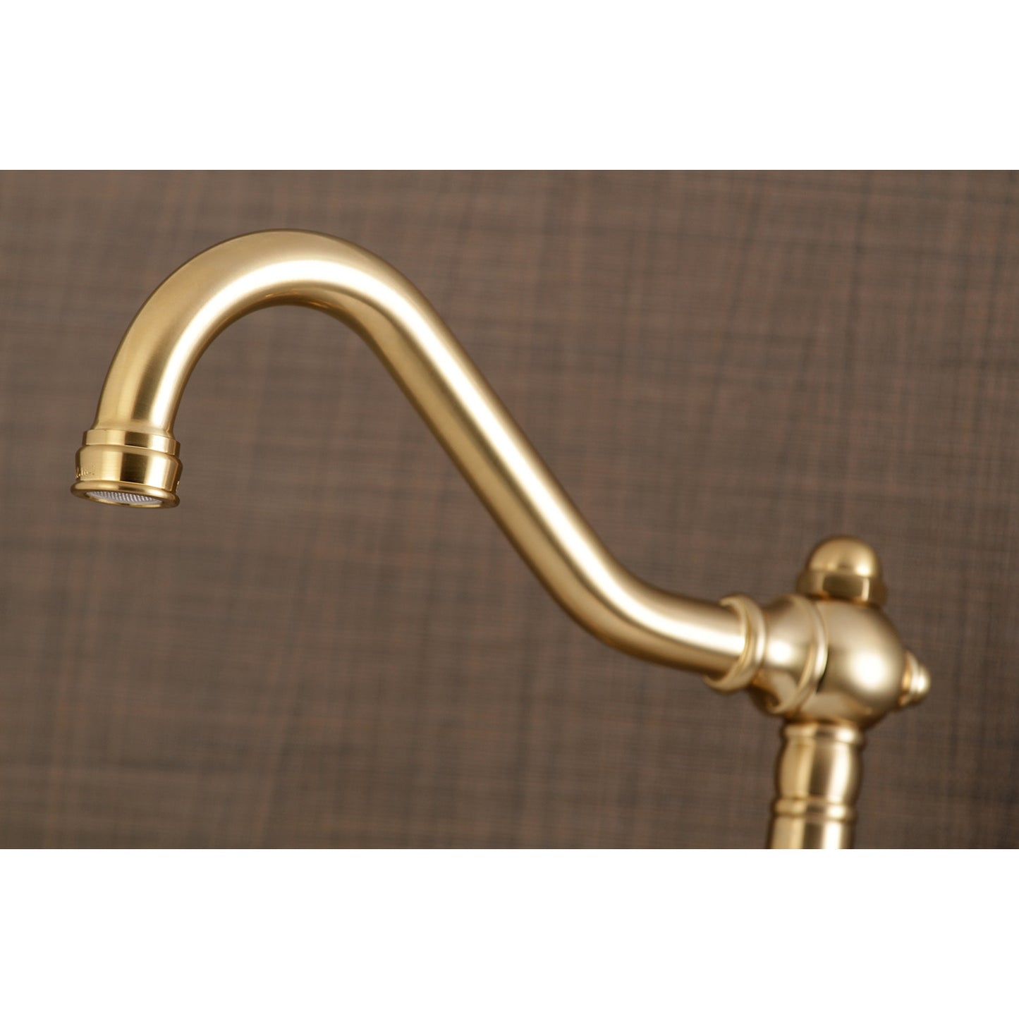 Detail of Kingston Brass KS3237AX brushed brass bathroom faucet on a brown background