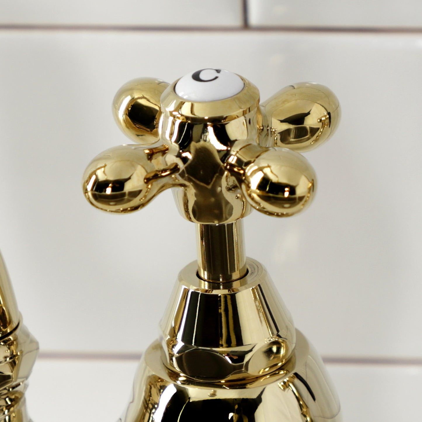 Close-up of Kingston Brass English Country Deck Mount Bridge Kitchen Faucet handle with vintage design.