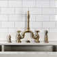 Kingston Brass KS7753AXBS Antique Brass  faucet installed over a kitchen sink with white tiled wall background