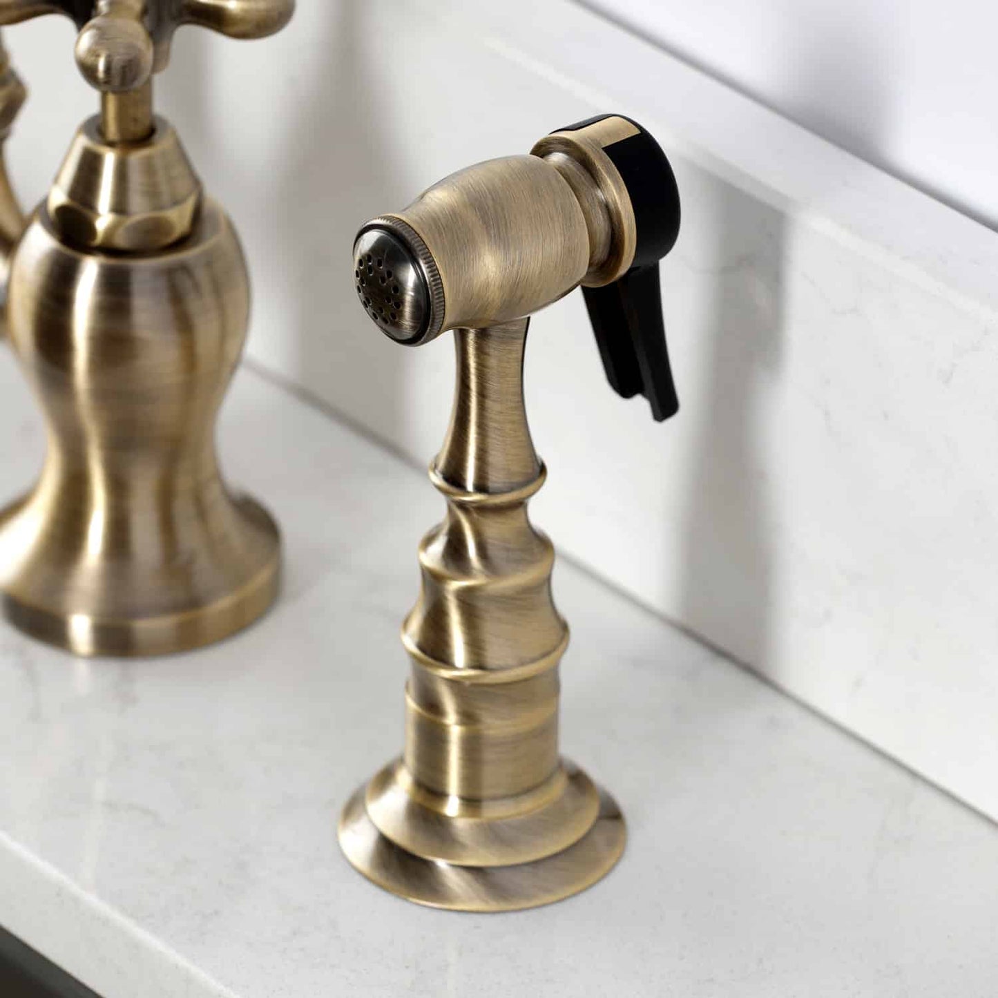 Kingston Brass English Country Deck Mount Bridge Kitchen Faucet sprayer from right side view on countertop.