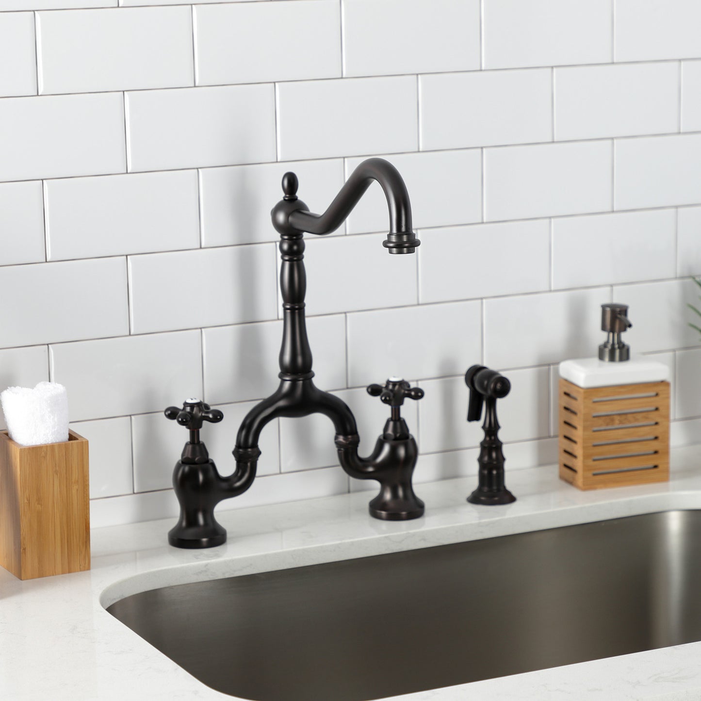 Kingston Brass KS7755AXBS oil rubbed bronze kitchen faucet set against a white tiled wall on a quartz countertop