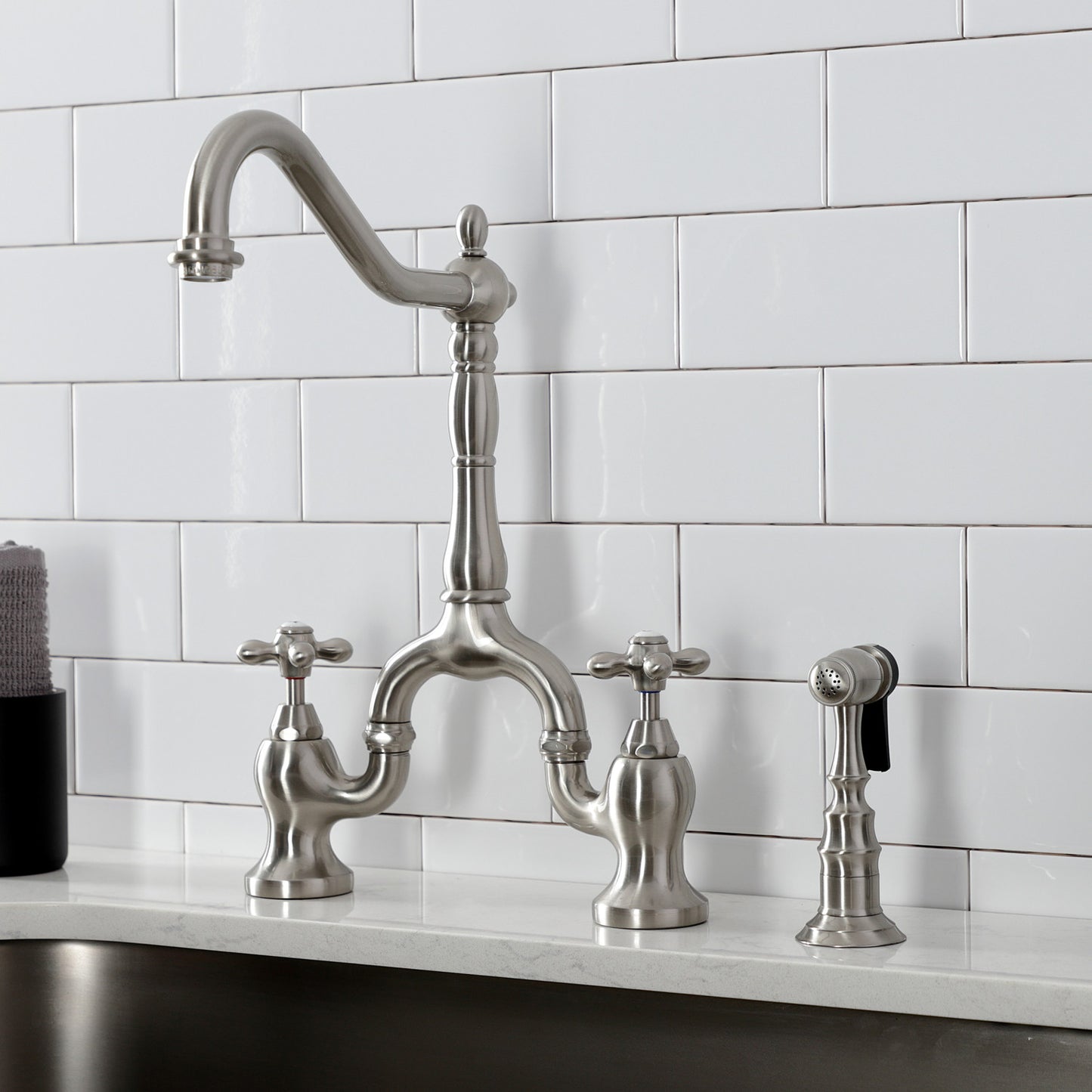 Kingston Brass KS7758AXBS brushed nickel kitchen faucet installed on a white quartz countertop
