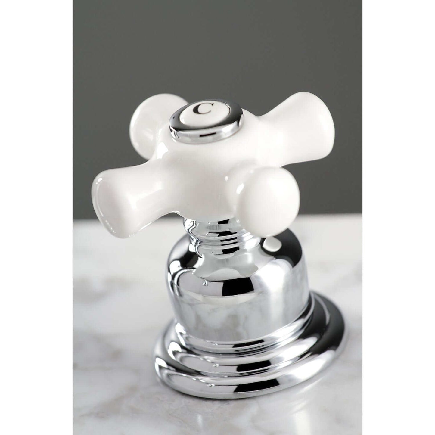 Close-up view of the KINGSTON Brass American Classic Widespread Bathroom Faucet with white cross handle and chrome base.