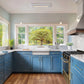 Modern kitchen with blue cabinets, white countertops, and a large window view.