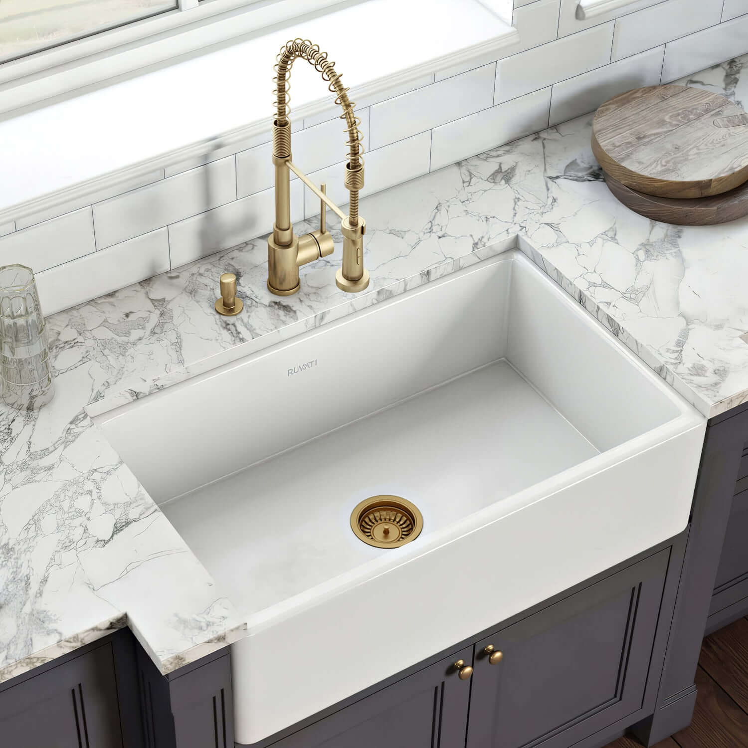 White kitchen sink with gold faucet and drain in a modern kitchen setting