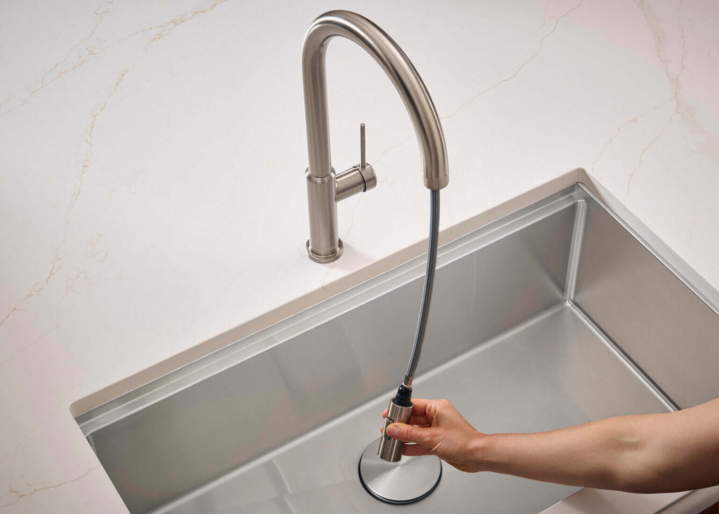 Ruvati RVF1237 Vestia Single-Handle Pull-Down Kitchen Faucet with Knurl Detail in use over a stainless steel sink.