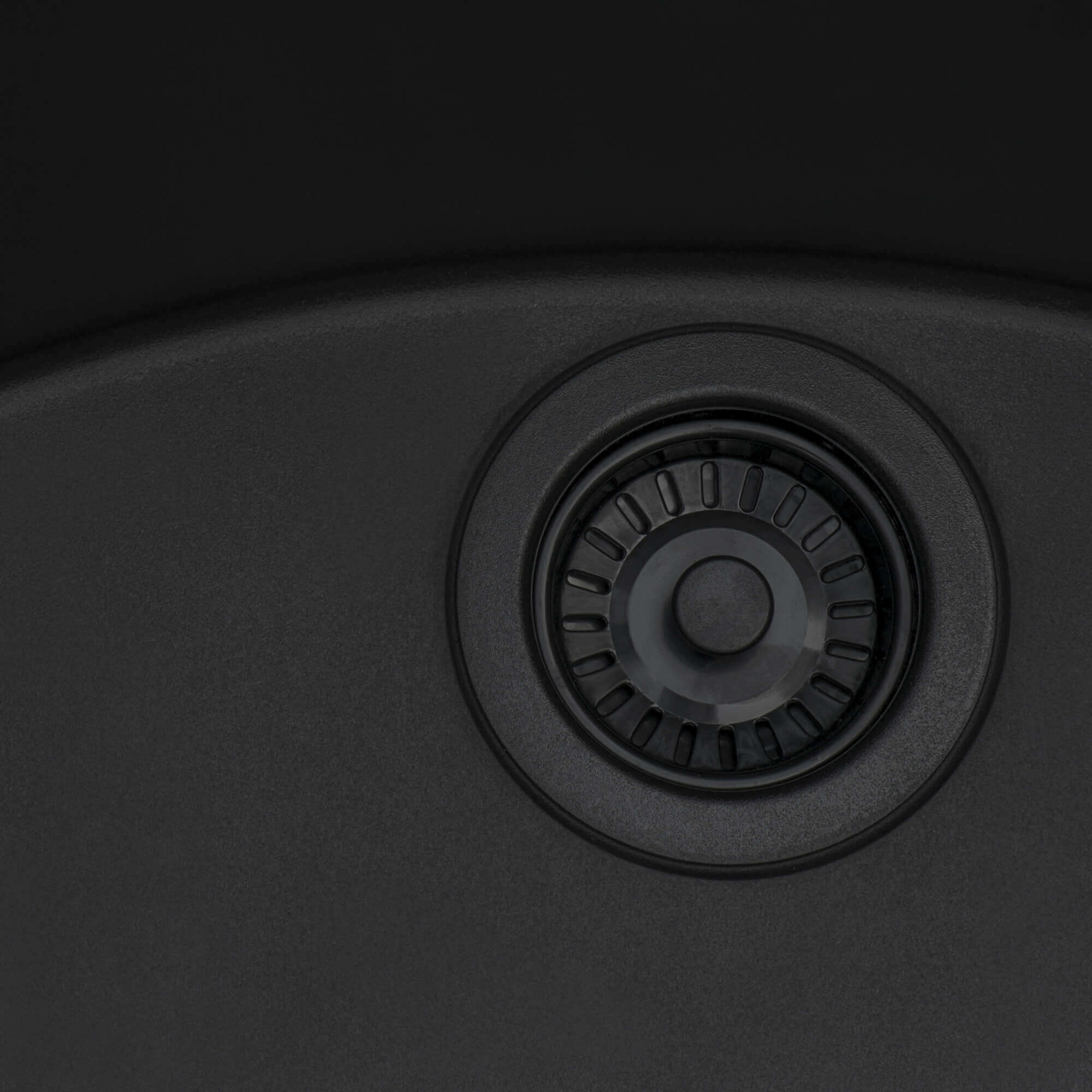 Close-up of Midnight Black Ruvati kitchen sink drain with black finish and strainer design.