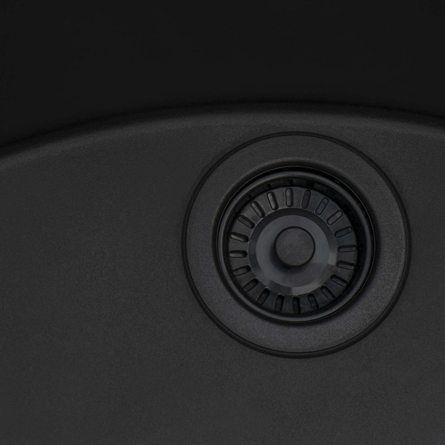 Close-up of Midnight Black Ruvati kitchen sink drain with black finish and strainer design.